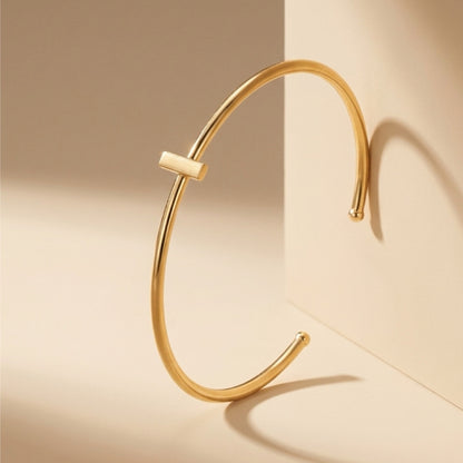 Dainty stackable Gold-plated bracelet with minimal bar on a beige surface 