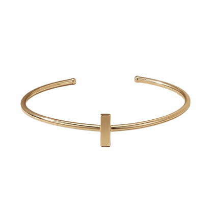 Dainty stackable Gold-plated bracelet with minimal bar on white surface 