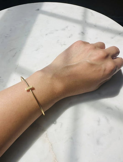 Gold bracelet on a wrist against a marble background