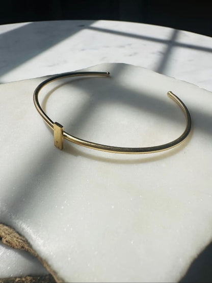 Gold-plated dainty stack bracelet on a marble white surface with natural light casting shadows.