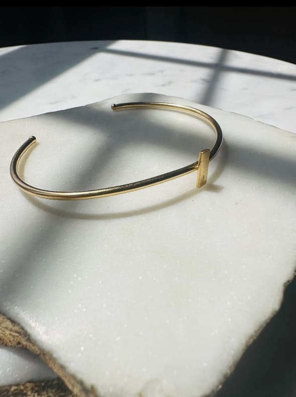 Dainty Gold-plated stack bracelet on a white stone surface with soft shadows
