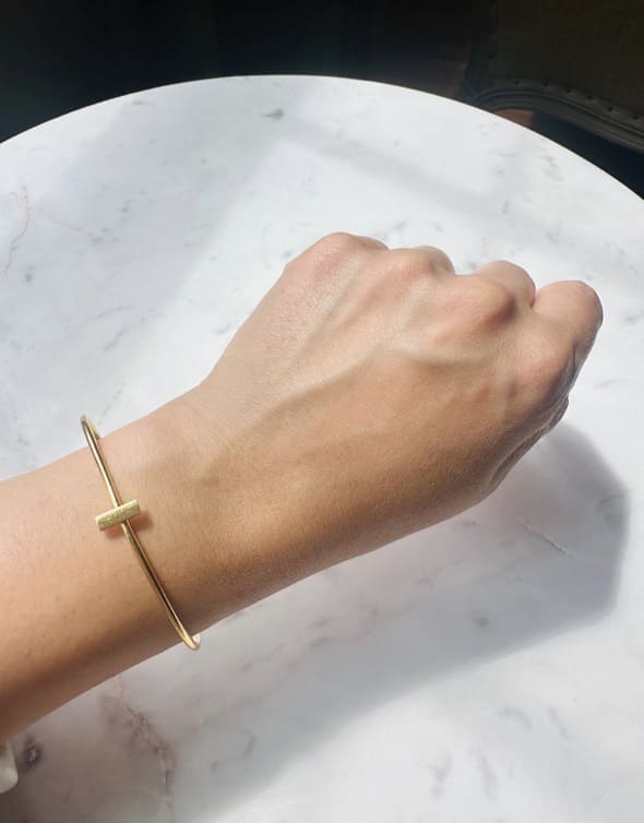 Gold-plated bracelet on a wrist against a marble background