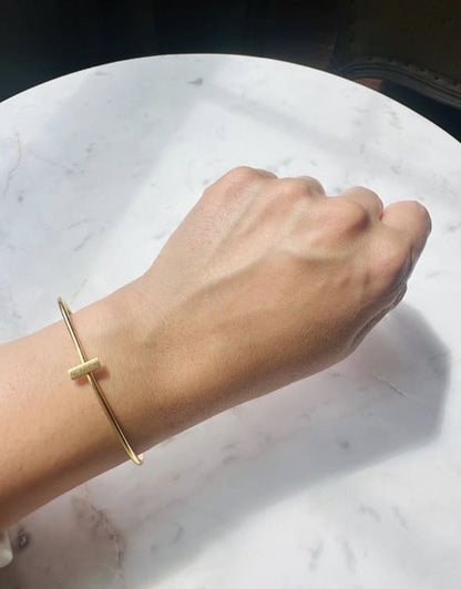 Gold-plated bracelet on a wrist against a marble background