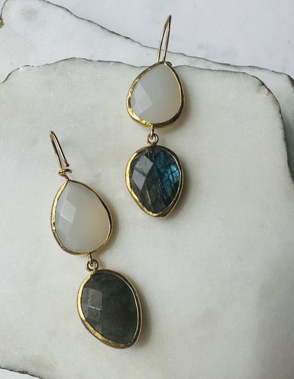 Handmade sustainable Gold-plated labradorite and snow quartz dangle earrings facing left on a marble surface