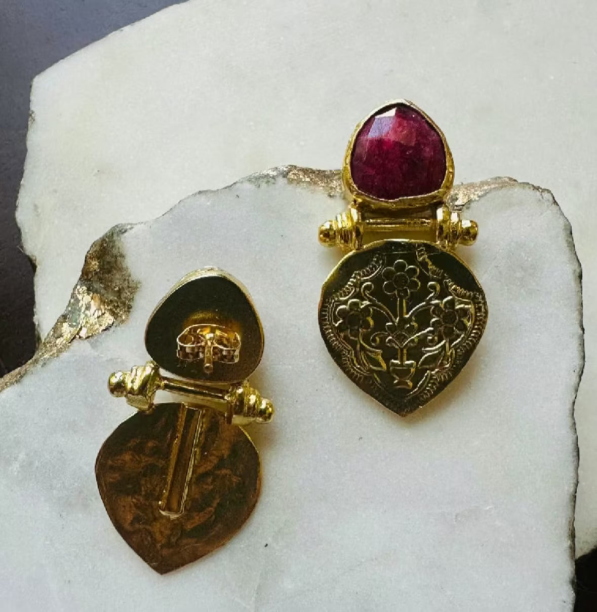 unique handmade sustainable Gold-plated ruby stud earrings with intricate etchings on a white stone background