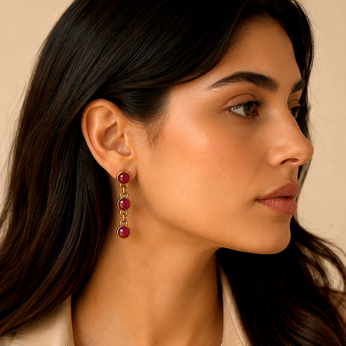 Indian Model with long brown hair wearing handmade gold-plated dangle earrings with three round faceted red rubies connected with linked chain 