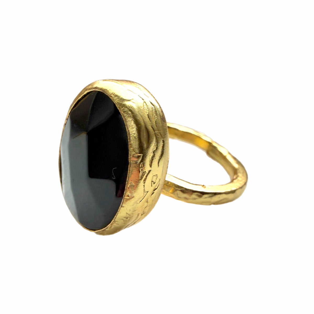A textured handmade gold ring featuring a large, faceted onyx gemstone ring against a plain white backdrop