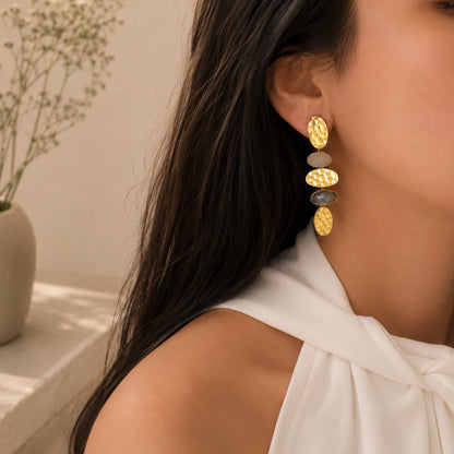 Lifestyle image close up of woman wearing handmade gold-plated snow Quartz and labradorite earrings with neutral background 