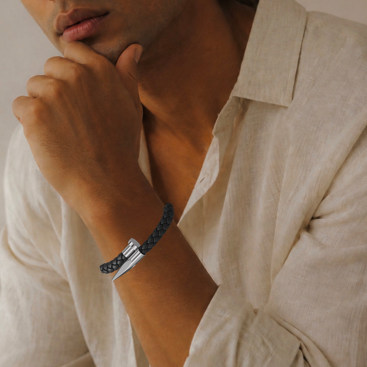 Man in banana republic beige linen button up collared shirt in natural light wearing a black woven silver nail design bracelet 