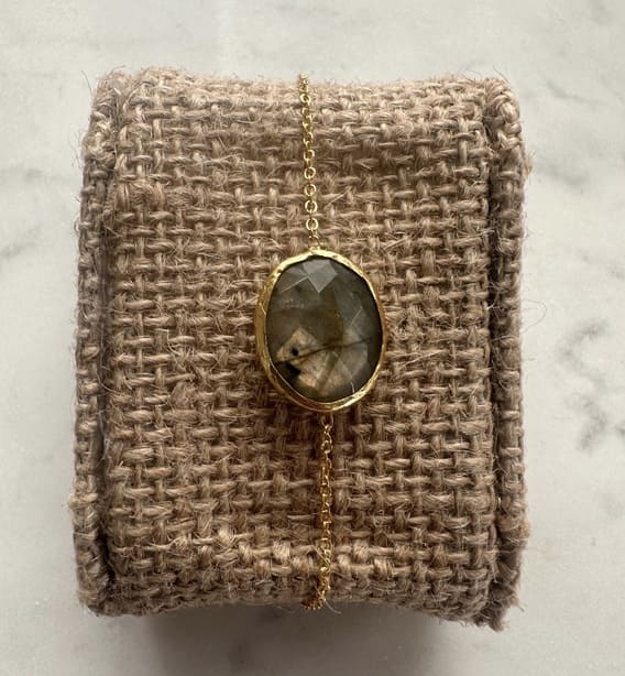 Gold minimal labradorite bracelet on a textured beige fabric background