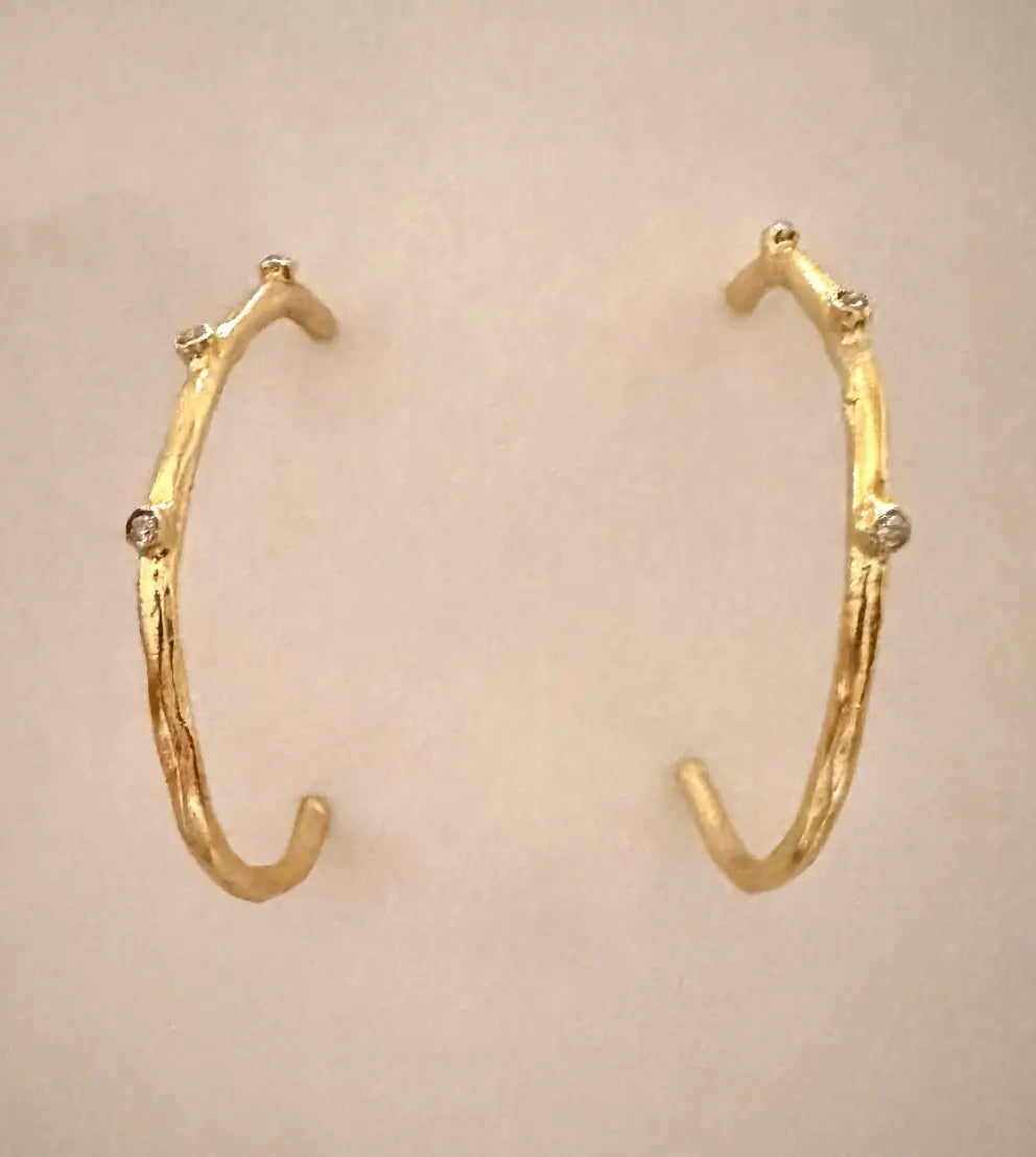modern and contemporary gold-plated cz elongated hoop earrings with beige background 