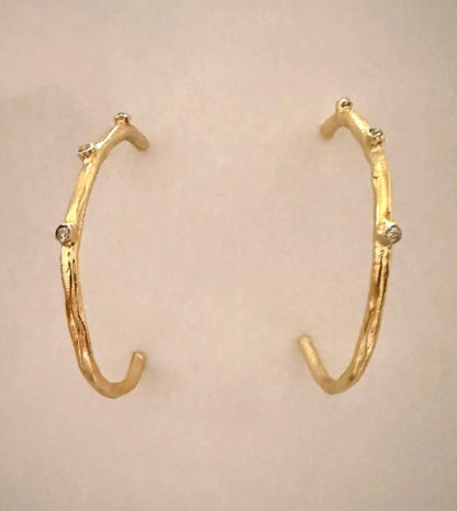 modern and contemporary gold-plated cz elongated hoop earrings with beige background 