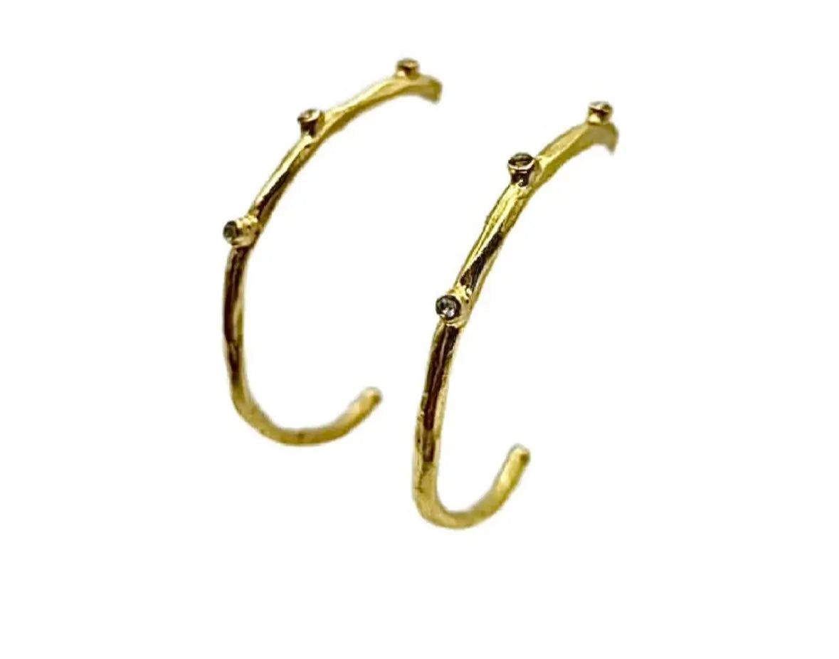 Modern and trendy handmade gold-plated textured elongated hoop earrings with cz against white background 