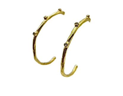 Modern and trendy handmade gold-plated textured elongated hoop earrings with cz against white background 