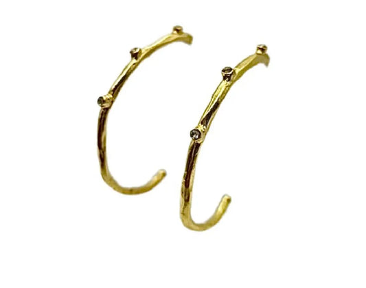 Modern and trendy handmade gold-plated textured elongated hoop earrings with cz against white background 
