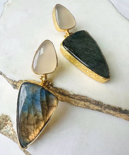 Pair of artisanal sustainable gold-plated snow Quartz and green stone bold statement earrings on a white Marble suface 