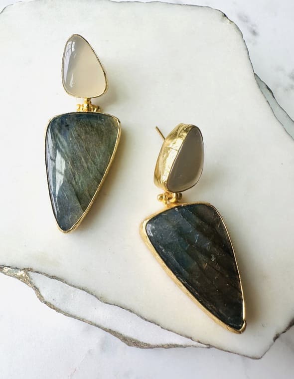 Handmade Gold-plated snow Quartz and green stone bold statement earrings  diagonally placed on a marble surface