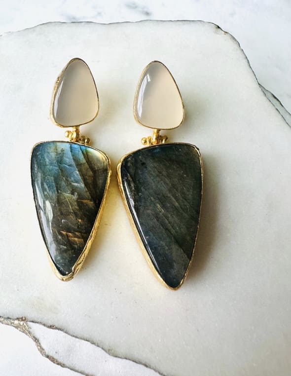 Pair of artisanal sustainable gold-plated snow Quartz and green stone bold statement earrings on a marble surface