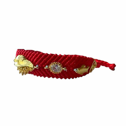 Left view of Handmade Red woven bracelet with gold-plated shell and evil eye accents on white surface