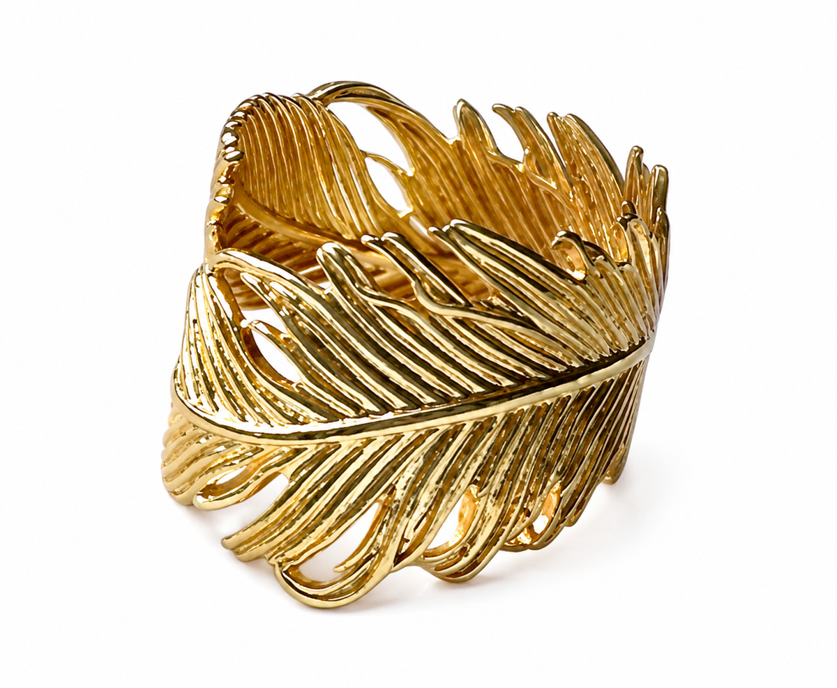 Angle of A gold-plated feather-shaped ring with textured, ribbed detailing, shown on a plain white background