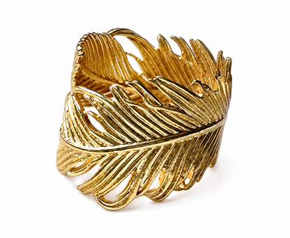 Angle of A gold-plated feather-shaped ring with textured, ribbed detailing, shown on a plain white background
