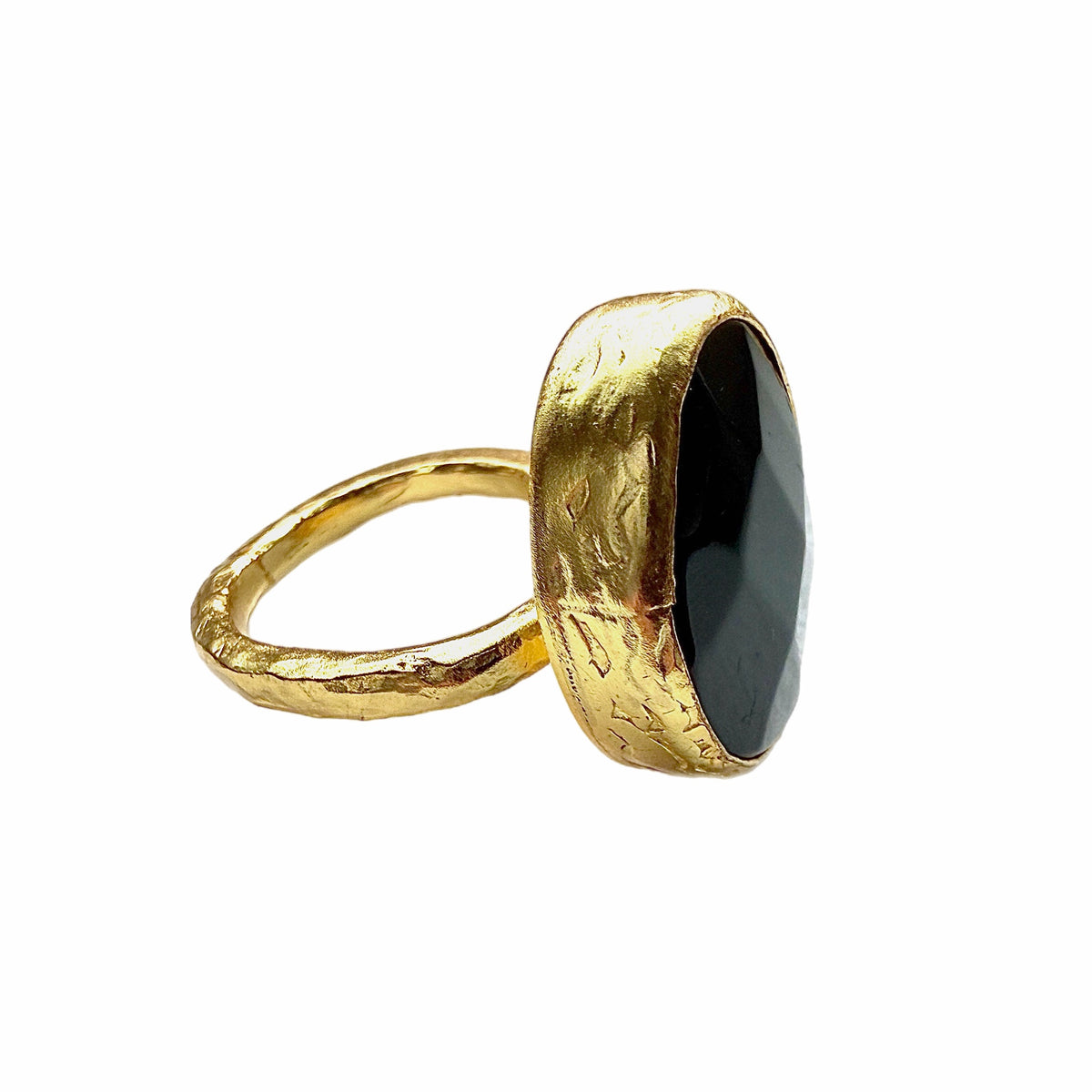A textured handmade gold ring featuring a large, faceted onyx gemstone ring against a plain white background