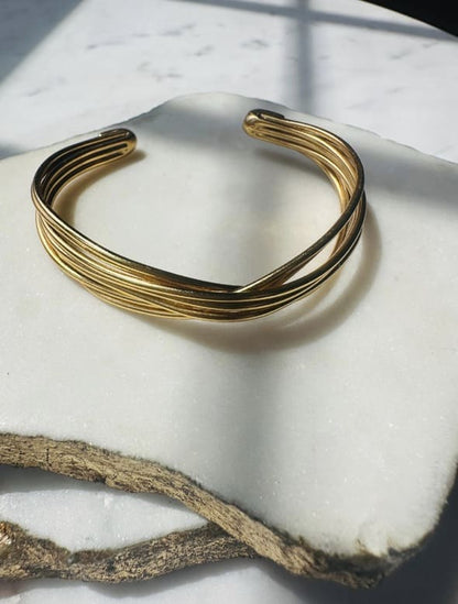Handmade sustainable Gold-plated wire bracelet on a white stone surface 