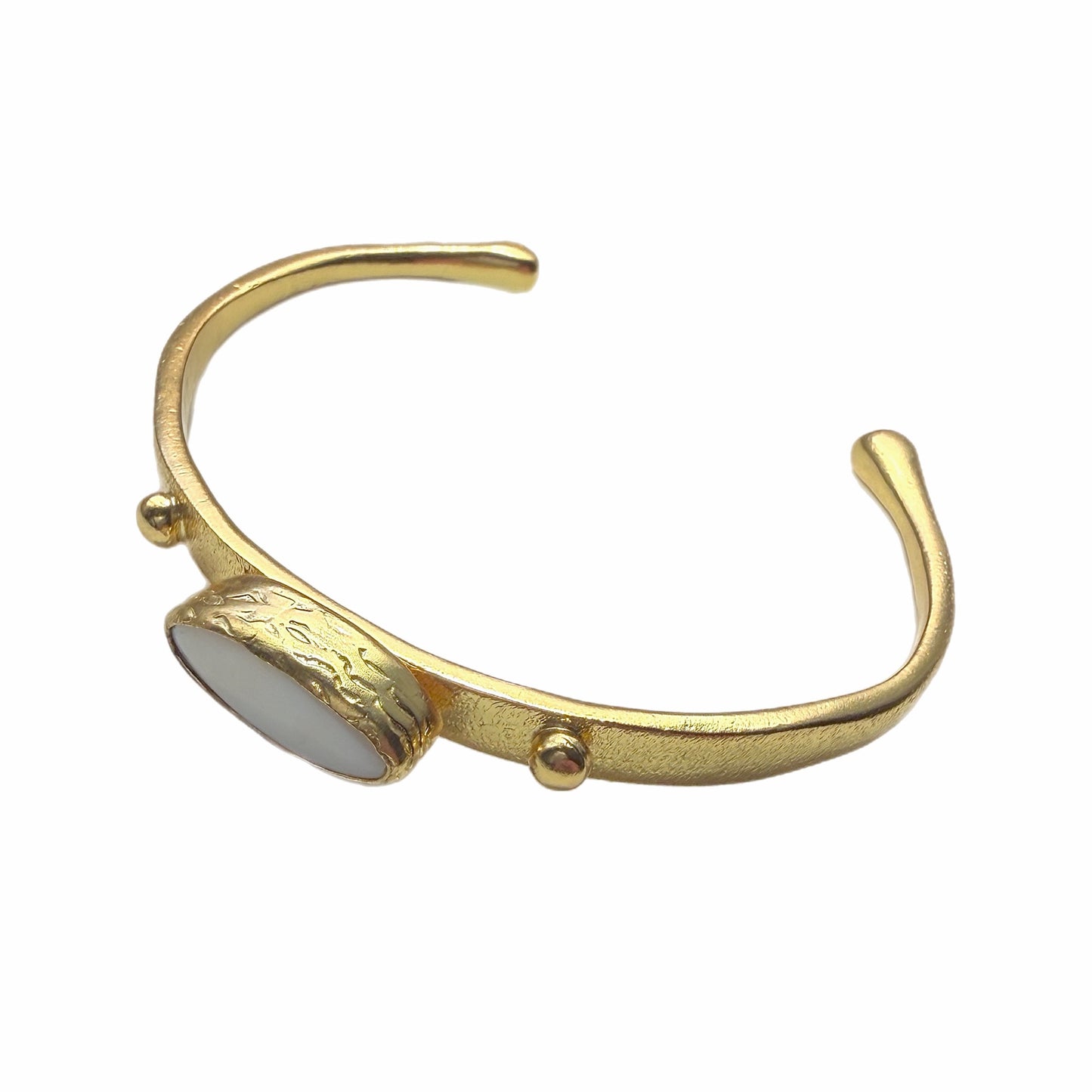 Gold-plated dainty bracelet with mother of pearl center laying on a white background  Facing left 
