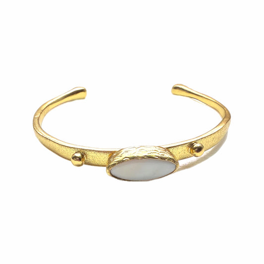 Gold-plated dainty bracelet with mother of pearl center laying on a white background 