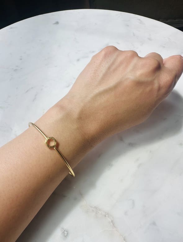 Gold-plated bracelet on a wrist against a marble background