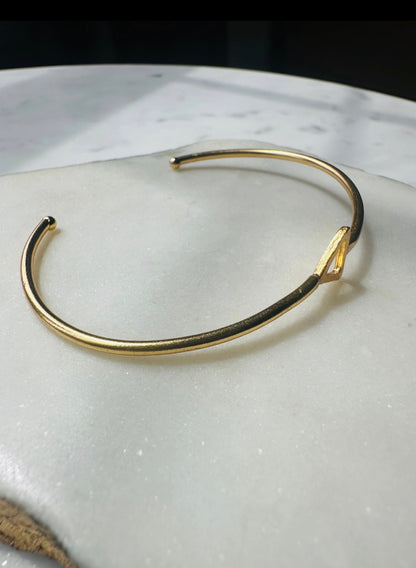 Gold-plated minimal bracelet on a white marble surface