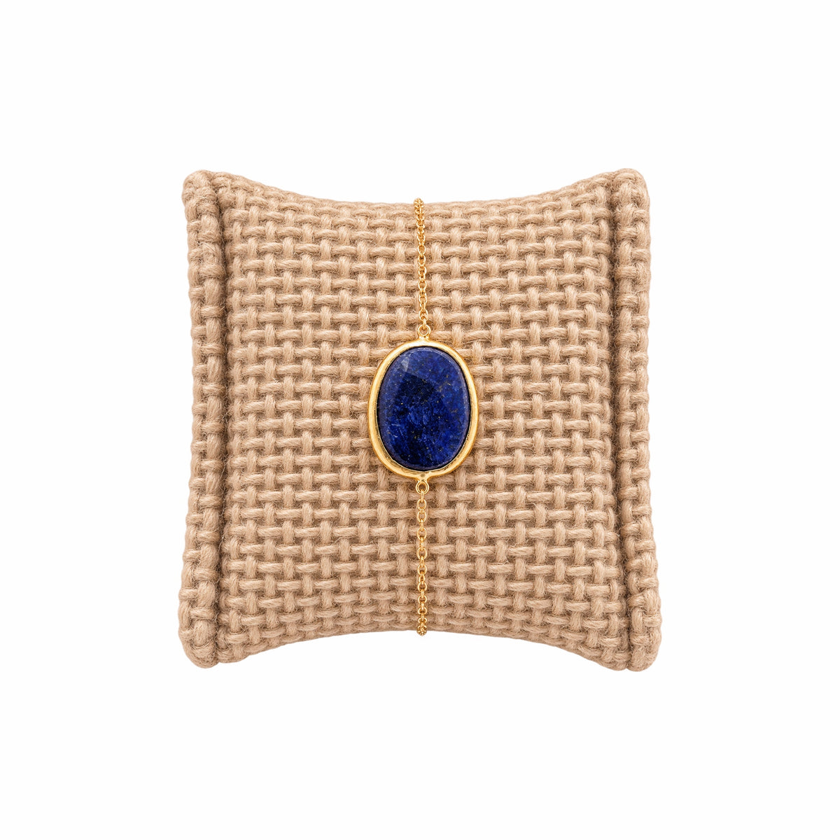 Textured beige cushion with a gold minimal chain bracelet with faceted blue lapis lazuli stone 