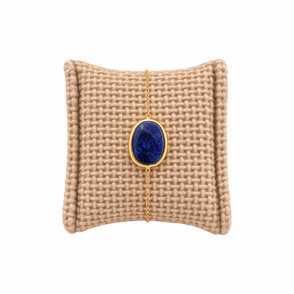 Textured beige cushion with a gold minimal chain bracelet with faceted blue lapis lazuli stone 