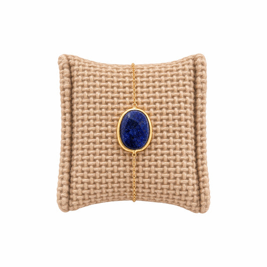 Textured beige cushion with a gold minimal chain bracelet with faceted blue lapis lazuli stone 