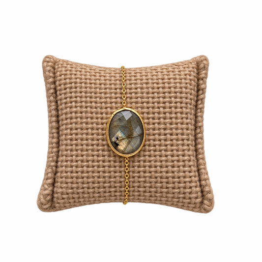 Textured beige cushion with a gold minimal chain bracelet with faceted blue labradorite stone