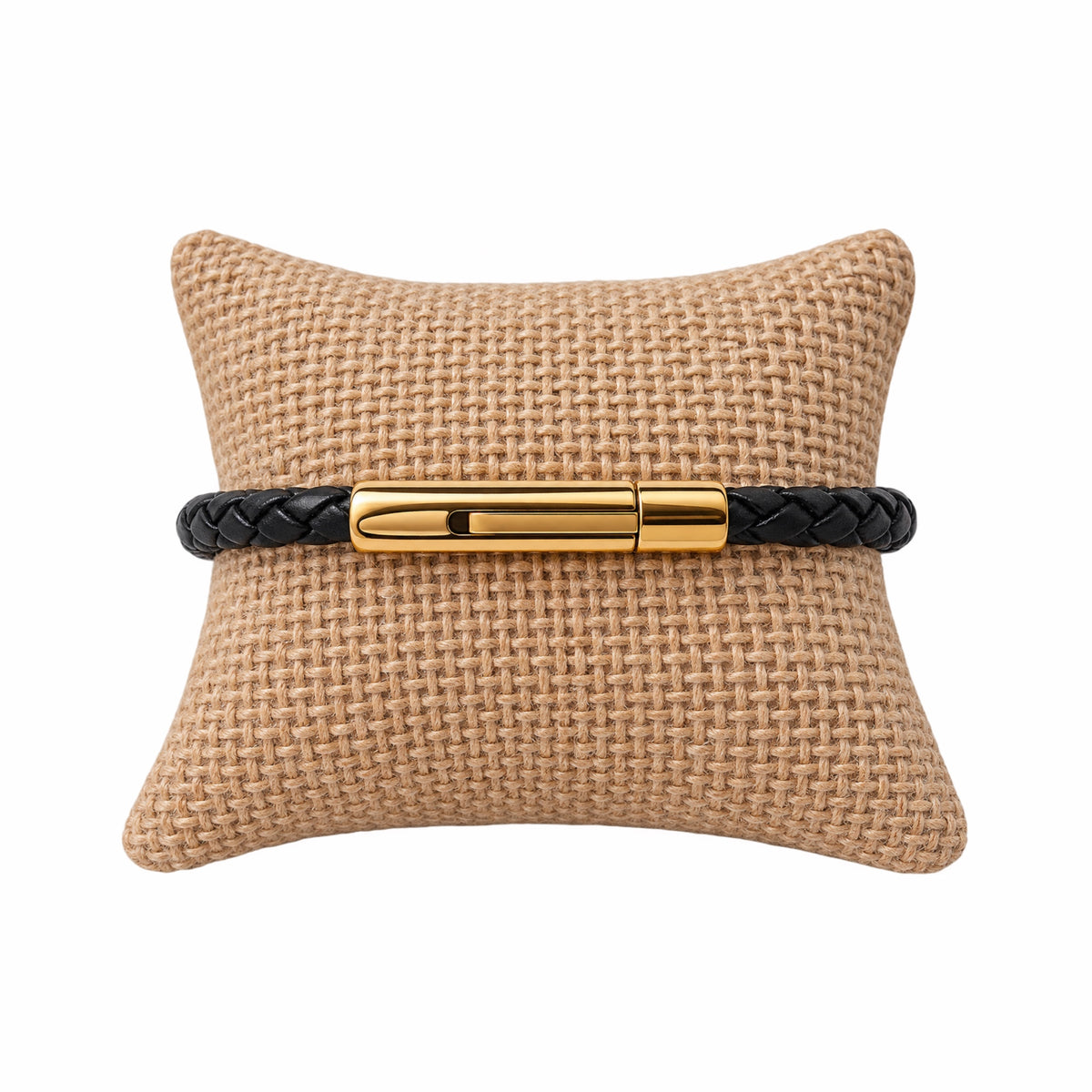Thin black leather braided bracelet with gold buckle on jute jewelry pillow 