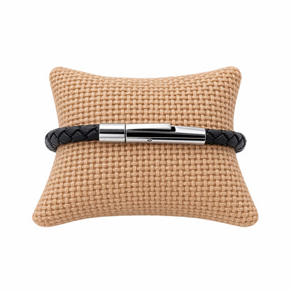 Thin black leather braided bracelet with silver buckle on jute jewelry pillow  