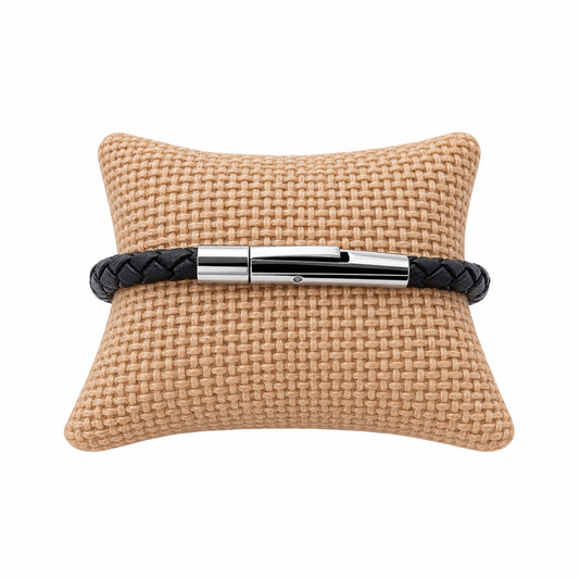 Thin black leather braided bracelet with silver buckle on jute jewelry pillow  