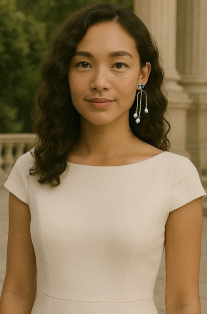 Woman in beige dress wearing Sustainable Handmade Gold Plated Labradorite and Pearl Contemporary Long Dangle Earrings Set on Marble Slabs with outdoor background 
