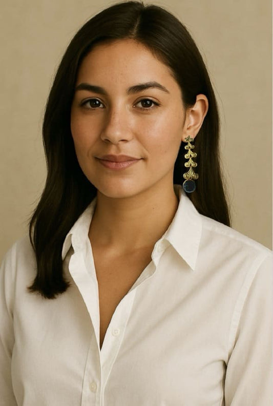 Woman wearing a white collared shirt with artisanal long dangle gold-plated sustainable earrings with black round onyx gemstone and a neutral background