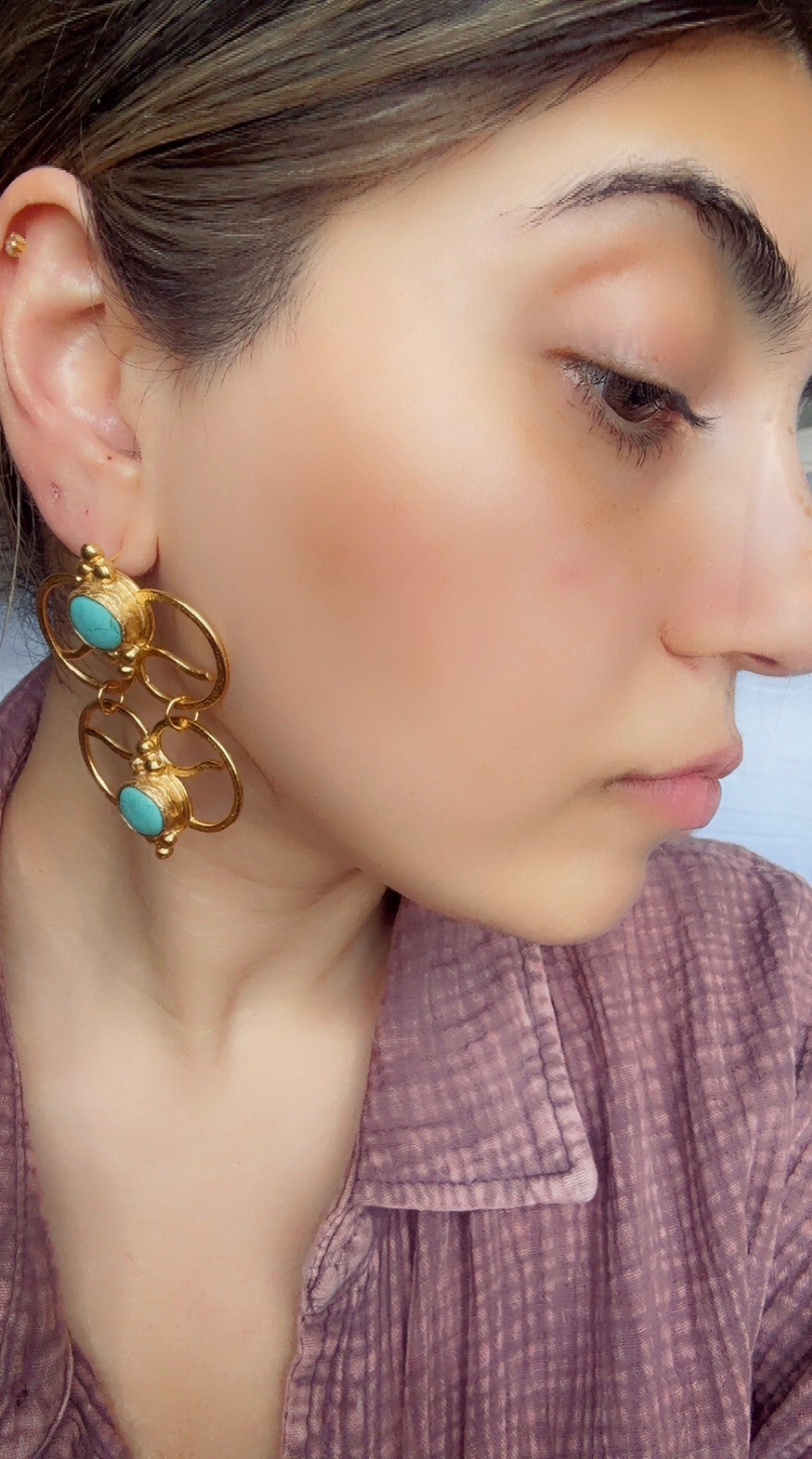 Woman wearing artisanal gold-plated bold geometric turquoise statement earrings 