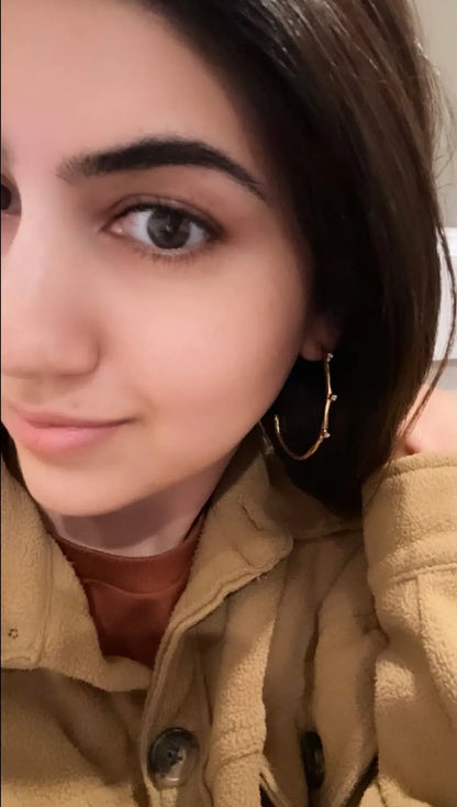 Woman wearing fleece and gold-plated modern cz elongated hoop earrings 