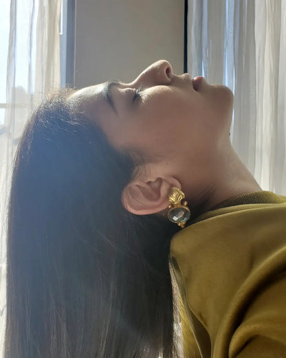 Woman wearing green top and beautiful gold-plated Fleur-de-Los labradorite earrings with a blurred background