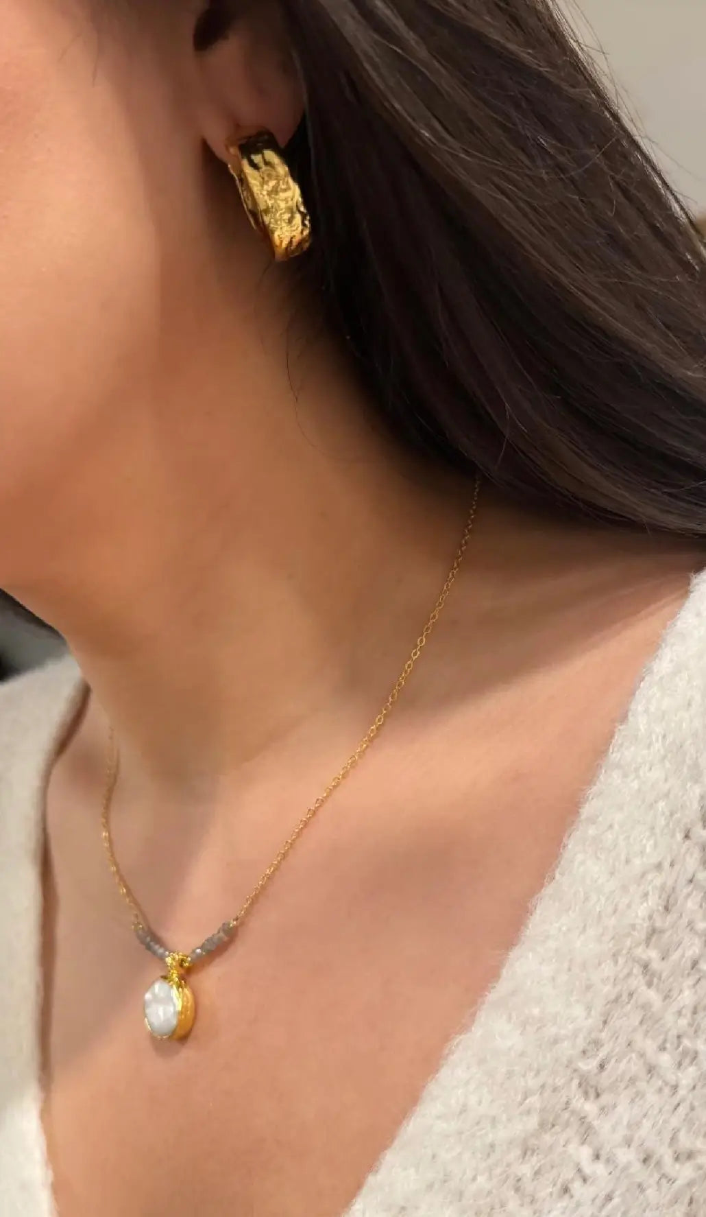 Close-up of a woman wearing gold-plated gray beaded and flat pearl necklace 