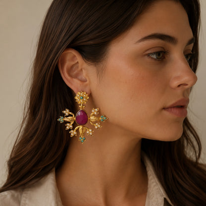 Woman with brown hair wearing Indian wedding handmade gold plated statement earrings with pearl, turquoise and embellishments and teardrop ruby center 