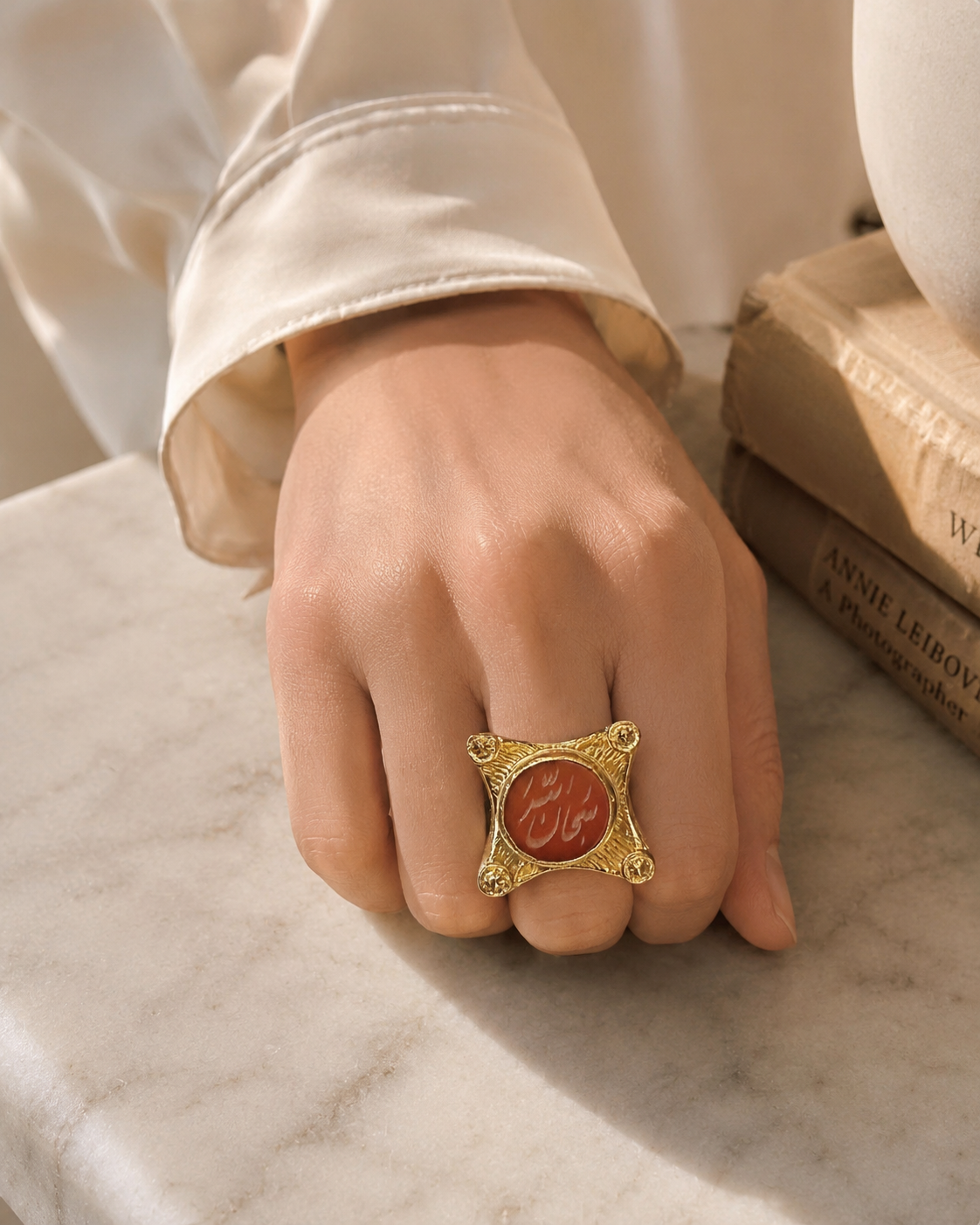 Woman’s hand wearing A gold-plated ring with Arabic calligraphy 'SubhanAllah' written in the center using semi-precious gemstone agate.