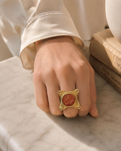 Woman’s hand wearing A gold-plated ring with Arabic calligraphy 'SubhanAllah' written in the center using semi-precious gemstone agate.