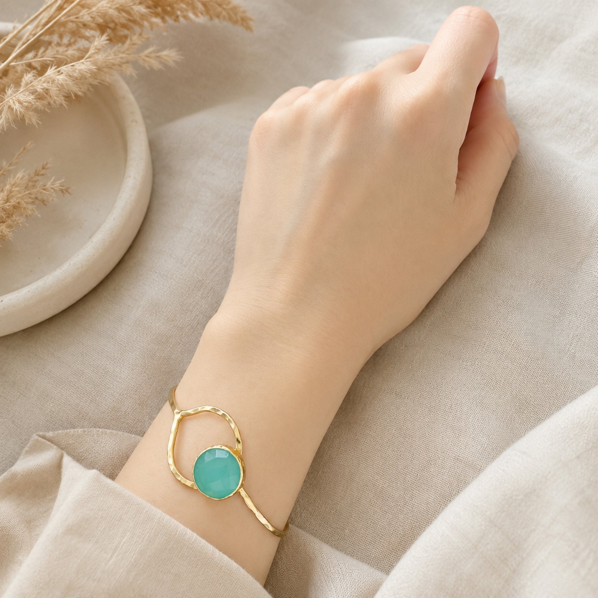 Gold-plated Aqua chalcedony bracelet on a wrist against a neutral background