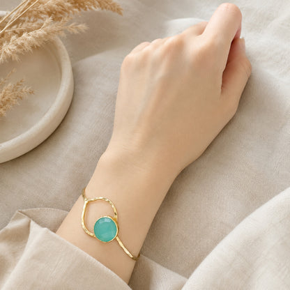 Gold-plated Aqua chalcedony bracelet on a wrist against a neutral background