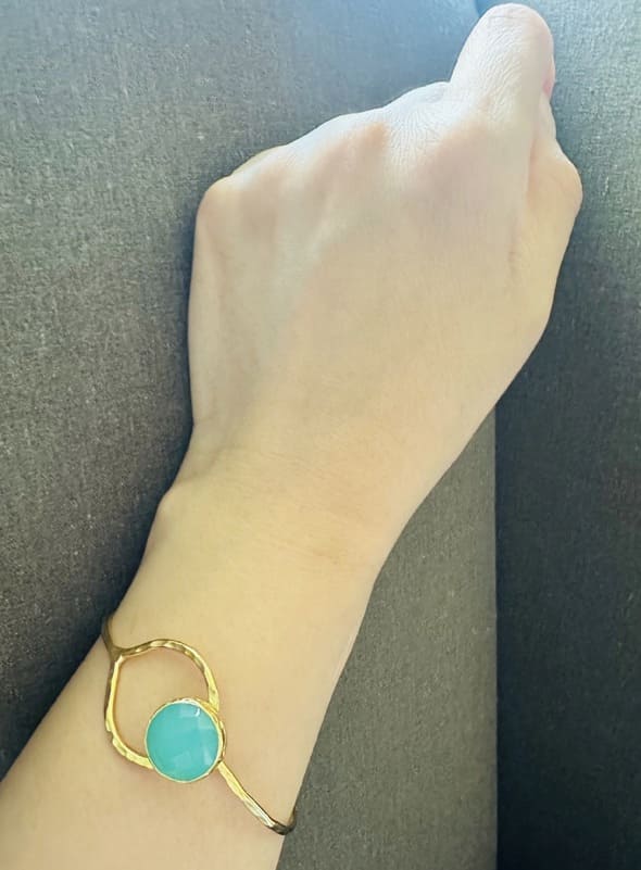 Gold-plated Aqua chalcedony bracelet on a wrist against a dark background